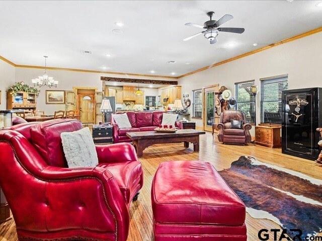 living room with ceiling fan with notable chandelier, wood-type flooring, and crown molding