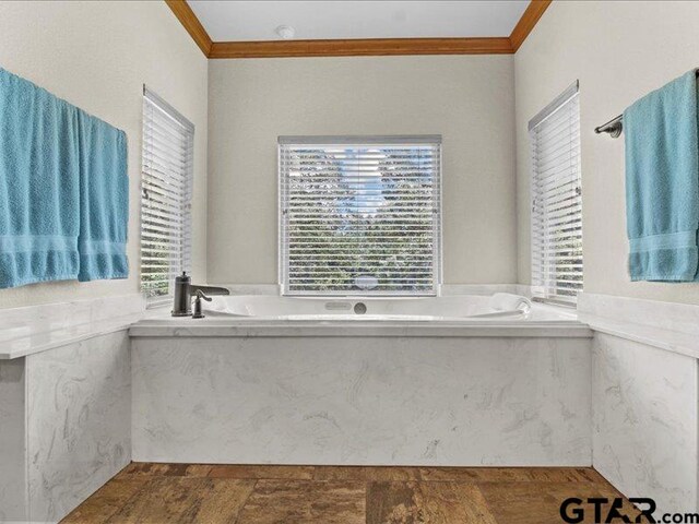 bathroom featuring a bathing tub, a wealth of natural light, and crown molding