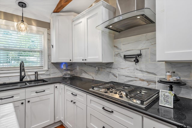 kitchen featuring tasteful backsplash, wall chimney exhaust hood, white cabinetry, and a sink