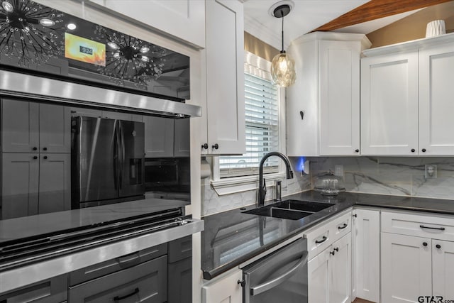 kitchen featuring white cabinets, stainless steel dishwasher, a sink, decorative light fixtures, and tasteful backsplash