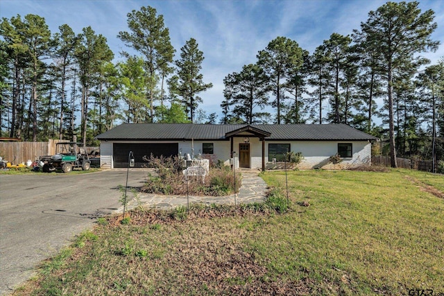 ranch-style home featuring fence, a garage, a front lawn, concrete driveway, and metal roof