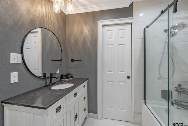 bathroom with a textured wall, vanity, crown molding, and shower / bath combination with glass door