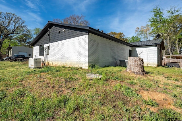 view of side of property featuring central air condition unit, brick siding, and ac unit