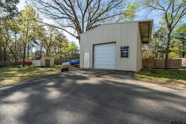 detached garage featuring driveway and fence