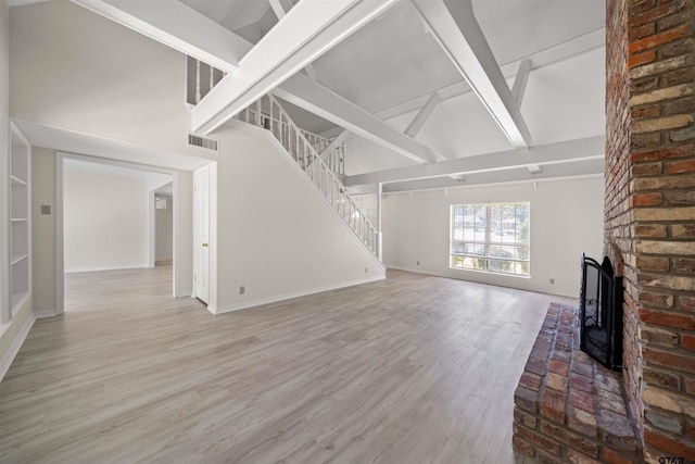 2110 Macbeth Ct, Tyler, TX 75703 - unfurnished living room with visible vents, wood finished floors, beam ceiling, high vaulted ceiling, and stairs