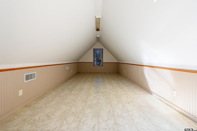 additional living space with lofted ceiling and wood walls