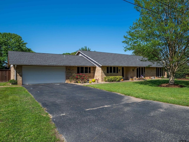 single story home featuring a front yard, a shingled roof, a garage, aphalt driveway, and brick siding