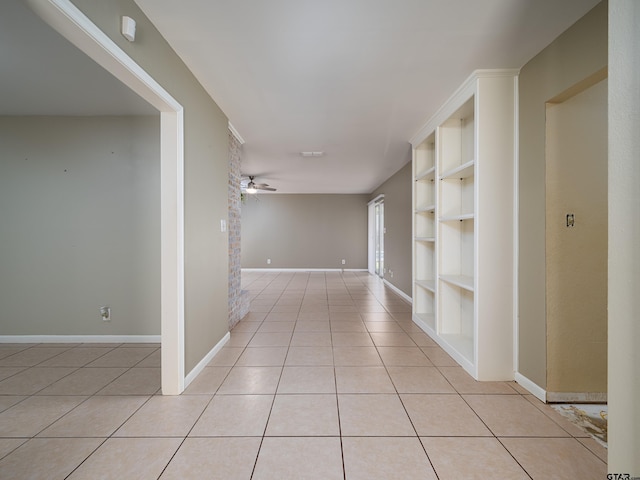 hall with light tile patterned floors, baseboards, and built in shelves