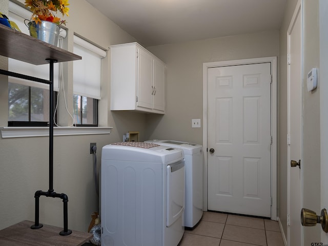 clothes washing area featuring light tile patterned flooring, washing machine and clothes dryer, and cabinet space
