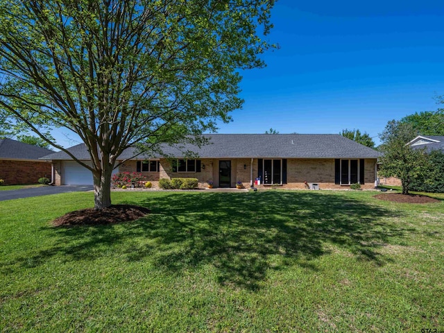 single story home with brick siding, driveway, an attached garage, and a front lawn