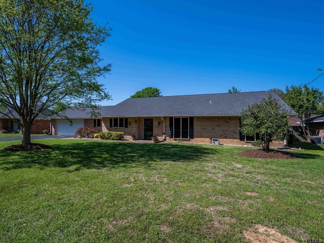 single story home featuring a shingled roof, brick siding, a front lawn, and an attached garage