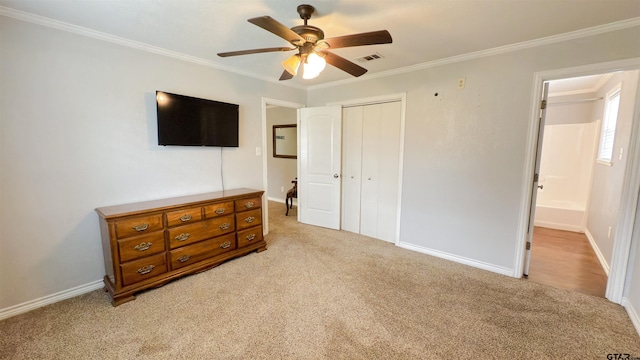 bedroom with ornamental molding, light colored carpet, ceiling fan, and a closet