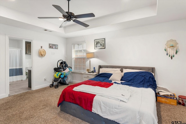 carpeted bedroom with a tray ceiling and ceiling fan