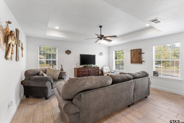 living room featuring light hardwood / wood-style floors, ceiling fan, and a tray ceiling