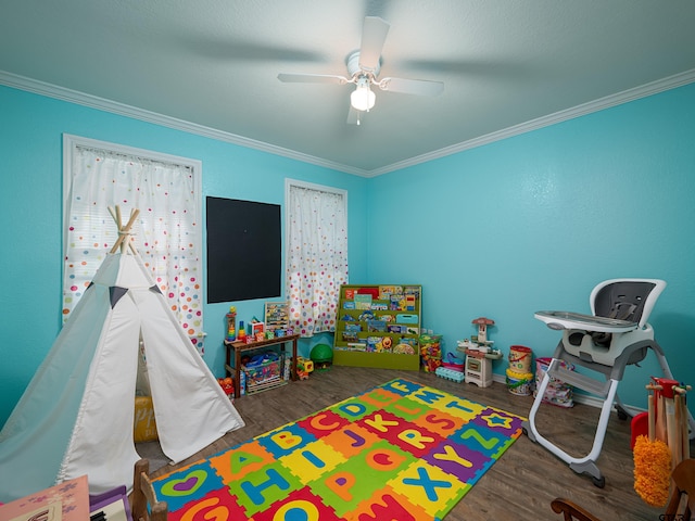 game room with dark wood-type flooring, ceiling fan, and crown molding