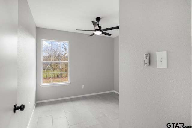 unfurnished room featuring a healthy amount of sunlight, ceiling fan, and baseboards