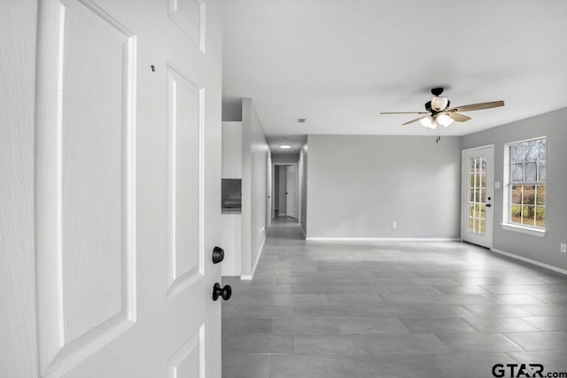 empty room with a ceiling fan and baseboards