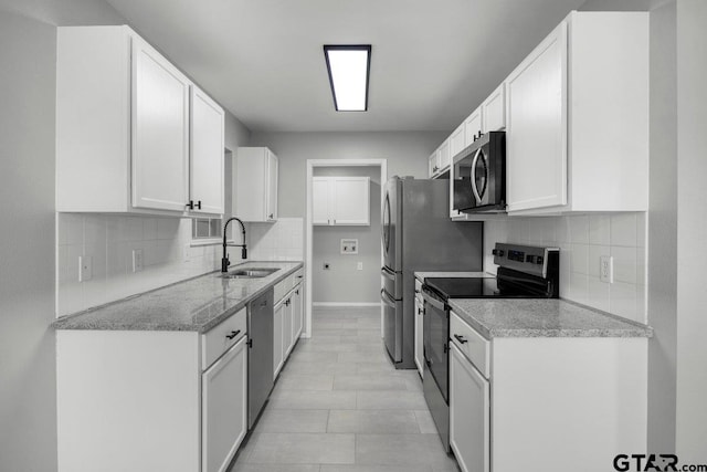 kitchen featuring appliances with stainless steel finishes, backsplash, a sink, and white cabinets