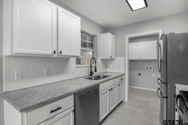 kitchen featuring stainless steel appliances, white cabinetry, a sink, and backsplash