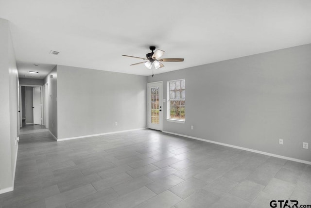 empty room featuring baseboards, visible vents, and a ceiling fan