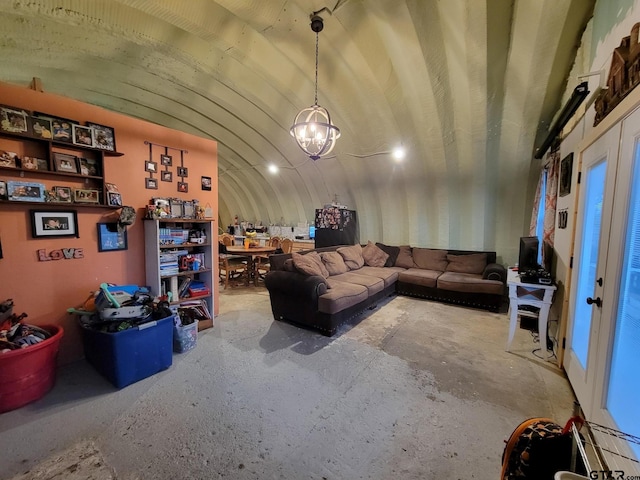 living room featuring lofted ceiling, a notable chandelier, and concrete floors