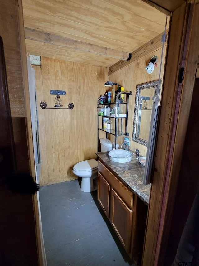 bathroom featuring wood walls, wood ceiling, toilet, and vanity