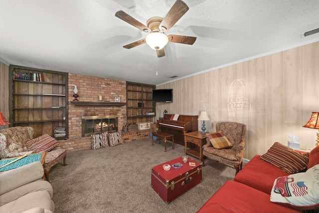 living room featuring a textured ceiling, a brick fireplace, crown molding, ceiling fan, and dark carpet