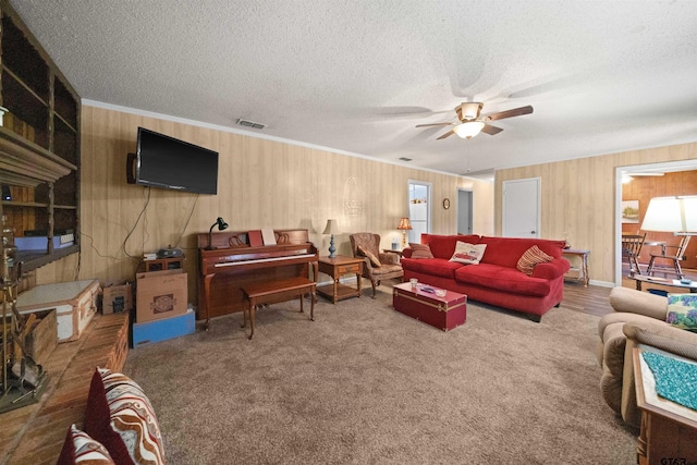 carpeted living room featuring ornamental molding, a textured ceiling, and ceiling fan