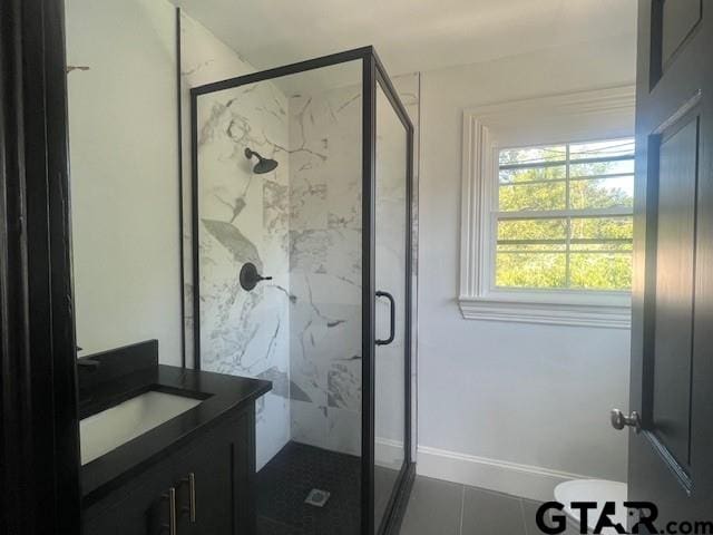 full bath with tile patterned flooring, a marble finish shower, vanity, and baseboards