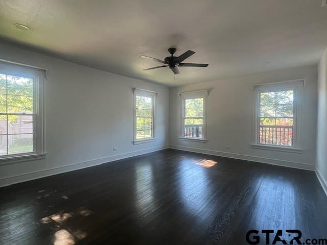 spare room featuring ceiling fan, baseboards, and dark wood-type flooring