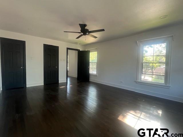 unfurnished bedroom featuring ceiling fan, dark wood-style flooring, and baseboards