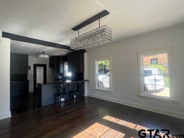 kitchen featuring dark countertops, hanging light fixtures, dark cabinets, a peninsula, and a kitchen breakfast bar