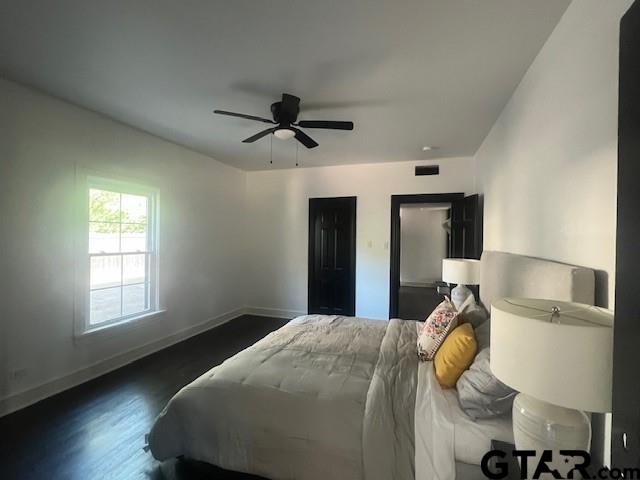 bedroom featuring dark wood-type flooring, a ceiling fan, visible vents, and baseboards