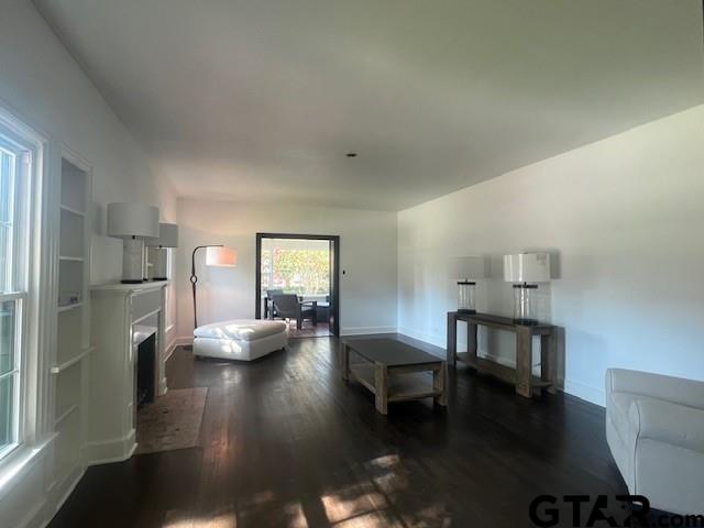 living area with a fireplace, baseboards, and dark wood finished floors