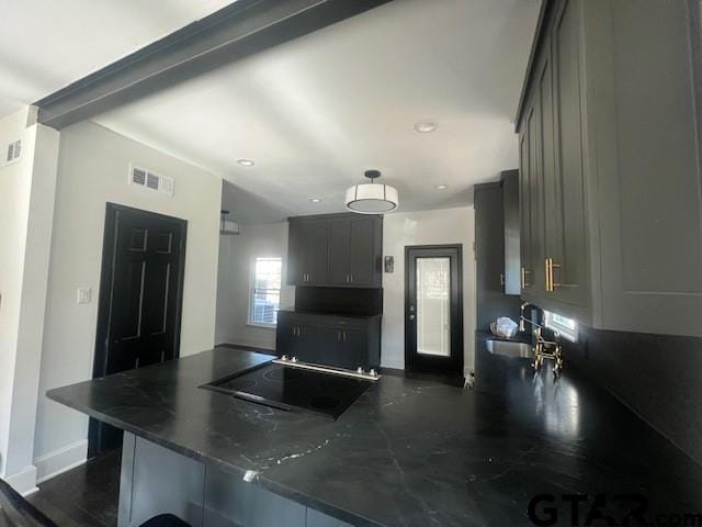 kitchen featuring a peninsula, dark countertops, black electric cooktop, and gray cabinets