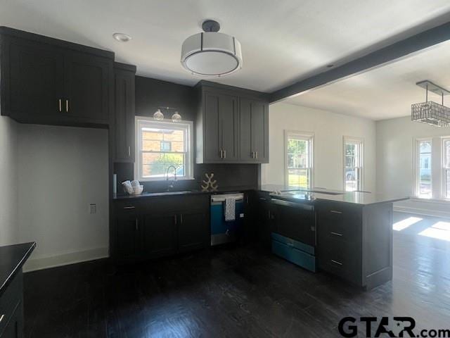 kitchen with a peninsula, a healthy amount of sunlight, beam ceiling, dishwasher, and dark wood finished floors