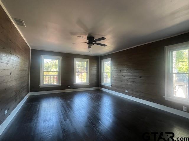 spare room with ceiling fan, dark wood finished floors, visible vents, and baseboards