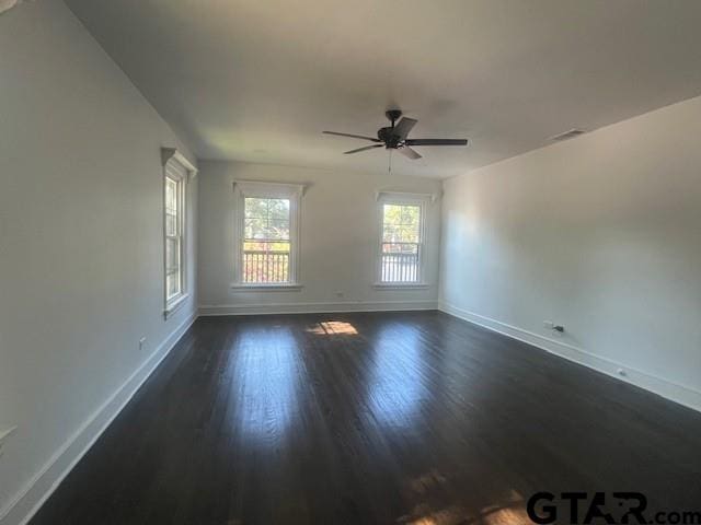 spare room with dark wood-type flooring, ceiling fan, and baseboards