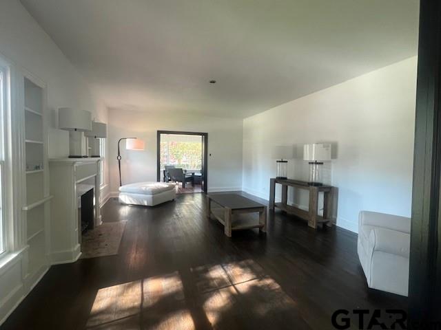 living area with dark wood finished floors, a fireplace, and baseboards