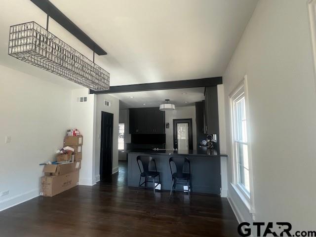 bar featuring dark wood-type flooring, visible vents, and baseboards