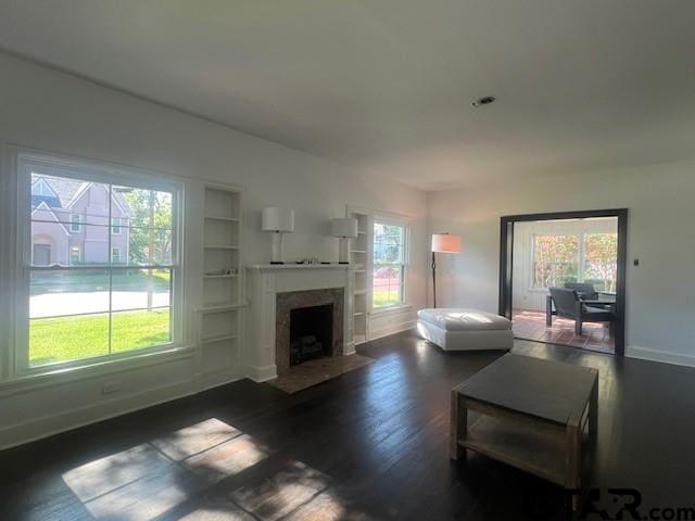 living area featuring dark wood-style floors, a fireplace, and a healthy amount of sunlight