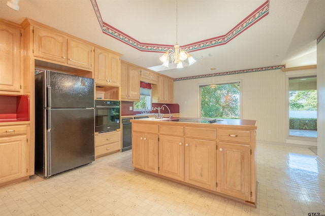 kitchen featuring light brown cabinets, an island with sink, black appliances, and a notable chandelier