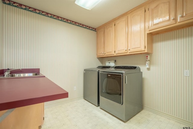 laundry area with cabinets, washing machine and dryer, and sink