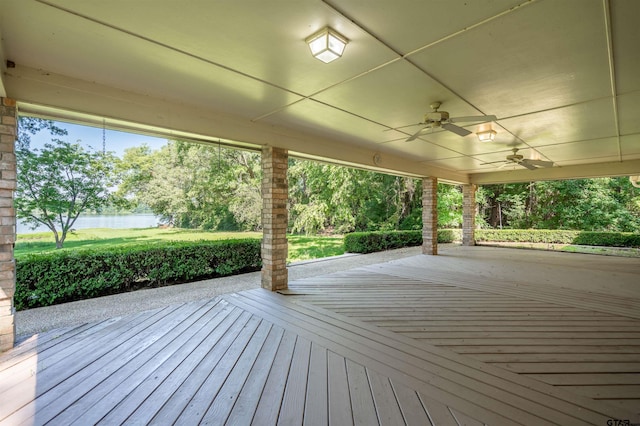 wooden terrace with a water view and ceiling fan