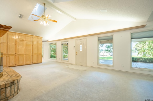 unfurnished living room with beamed ceiling, a skylight, light colored carpet, and a healthy amount of sunlight