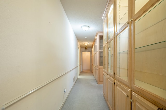 corridor with a textured ceiling and light colored carpet