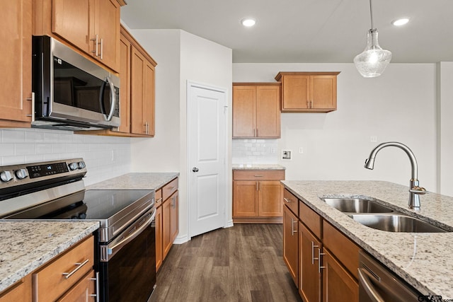 kitchen featuring sink, dark wood-type flooring, light stone counters, decorative light fixtures, and appliances with stainless steel finishes