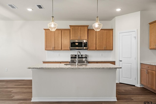 kitchen with sink, dark hardwood / wood-style flooring, an island with sink, and appliances with stainless steel finishes