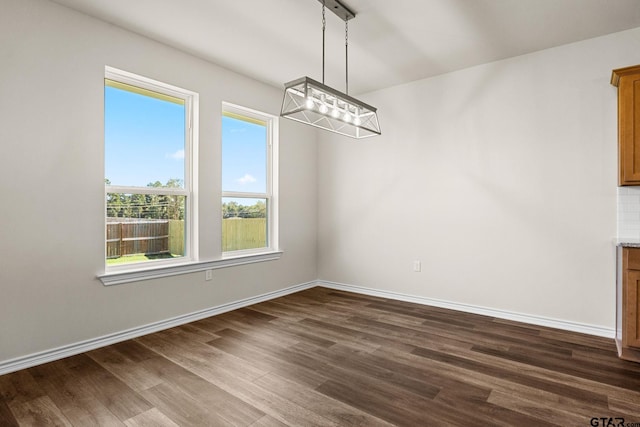 unfurnished dining area featuring dark hardwood / wood-style floors and a chandelier