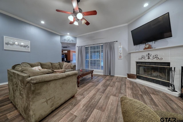 living room featuring crown molding, a ceiling fan, a brick fireplace, wood finished floors, and baseboards